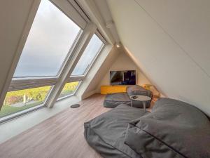 a attic room with two beds and a chair at Happy Beach 50 in Colijnsplaat