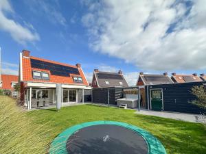 una casa con un patio trasero con un trampolín en el patio en Coast and Calm 63, en Colijnsplaat