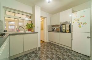 Una cocina con gabinetes blancos y un refrigerador blanco. en Newport by M4, en Newport