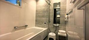 a white bathroom with a tub and a toilet at 新築江の電腰越駅前徒歩1分鎌倉江の島観光に最適鎌倉腰越駅前ｂ棟 in Kamakura