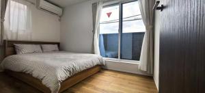 een slaapkamer met een bed en een groot raam bij Kamakura Koshigoe Ekimae B in Kamakura
