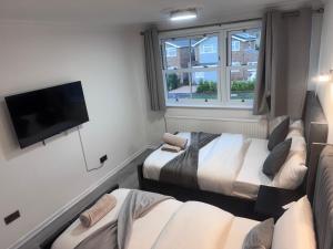 une chambre avec deux lits et une télévision à écran plat dans l'établissement Ama comfort Stay, à Hythe