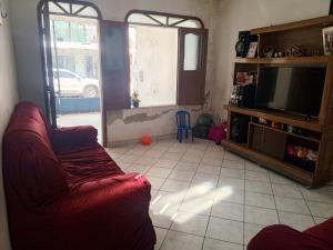 a living room with a red couch and a television at Quarto próximo aeroporto, mangueirão, rodoviária, UFPA in Belém