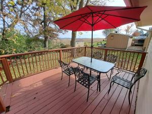 a table and chairs on a deck with a red umbrella at Location! Large Home, Country Views, Entertainment in Dubuque