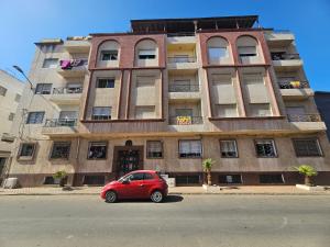 a red car parked in front of a building at Appartement famille plage in El Jadida
