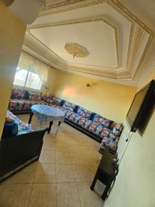 a room with couches and a table and a tv at Appartement famille plage in El Jadida