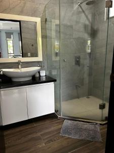 Un baño con lavabo y ducha de cristal. en Surf VIP location, en Cóbano