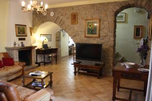 a living room with a tv and a stone wall at Agriturismo Casale 1921 in Torre le Nocelle