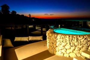 a large swimming pool with a stone wall next to a building at Chalé Boutique - Spa - Sauna seca , Jacuzzi , Rede suspensa in Campos do Jordão
