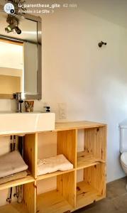 ein Badezimmer mit Waschbecken und Holzregalen in der Unterkunft La Parenthese 