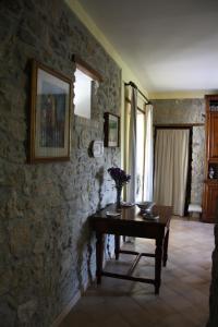 Habitación con mesa y pared de piedra. en Agriturismo Casale 1921, en Torre le Nocelle
