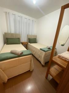 een kamer met 2 bedden en een spiegel bij Conforto e aconchego em São João del-Rei in São João del Rei