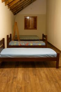 duas camas em um quarto com piso de madeira em Casa da família Castro em Capão da Canoa