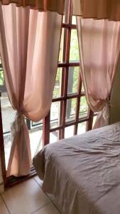 サンルイスにあるEl descanso de los colibrisのベッドとカーテンのついた窓のある寝室