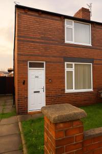 Casa de ladrillo con puerta blanca y ventanas en Platt Bridge Contractor Stays-One Bedroom house, en Abram