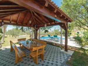 a wooden pavilion with a table and chairs and a pool at Holiday Home Marin AS with Pool in Trbounje