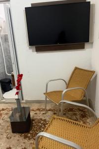 a living room with two chairs and a flat screen tv at Kitnet Dream House 1 in Bayeux