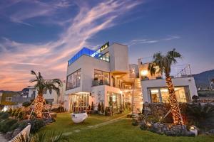 ein großes weißes Haus mit Palmen davor in der Unterkunft Seogwipo Dawa Pool Villa Pension in Seogwipo