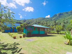 a small blue house with a mountain in the background at Chalet Familiale Vue Mer et Coucher de Soleil Moorea in Moorea