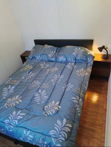 ein Bett mit einer blauen Bettdecke darauf in der Unterkunft Cómoda casa cerquita de la playa in Cuchilla Alta