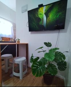 ein Wohnzimmer mit einem TV und einer Topfpflanze in der Unterkunft Cómoda casa cerquita de la playa in Cuchilla Alta