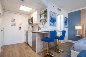 a kitchen with a counter and two blue chairs in a room at Studio with Private Terrace and Volcano Bay View Near Epic Universe in Orlando