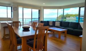 a living room with a table and chairs and a couch at Sails Apartments in Forster