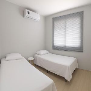 ein weißes Zimmer mit zwei Betten und einem Fenster in der Unterkunft Apartamento Ponta Negra Manaus - Próximo ao Aeroporto in Manaus