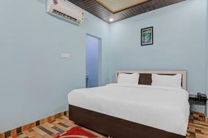 a bedroom with a white bed and a blue wall at Hotel O Drip Inn in Bheta