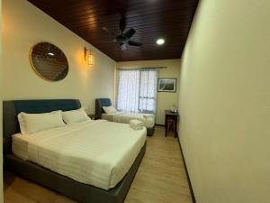 a bedroom with a bed and a couch and a fan at Tranquera House in Ranau