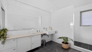 ein weißes Badezimmer mit Waschbecken und Topfpflanze in der Unterkunft Pacific Piers in Coffs Harbour + 19 Fotos