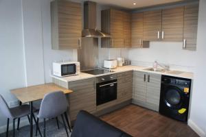 La cuisine est équipée de placards en bois, d'un évier et d'un lave-vaisselle. dans l'établissement Melbourne House Gem Stylish 2-bed In City Centre, à Accrington