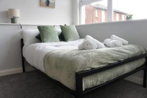 un lit avec des oreillers verts et blancs et une fenêtre dans l'établissement Melbourne House Gem Stylish 2-bed In City Centre, à Accrington