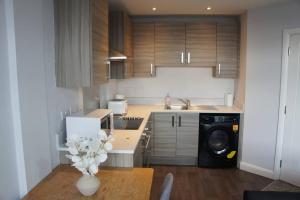 une cuisine avec des placards en bois et une table avec un lave-linge dans l'établissement Melbourne House Gem Stylish 2-bed In City Centre, à Accrington 24 autres photos