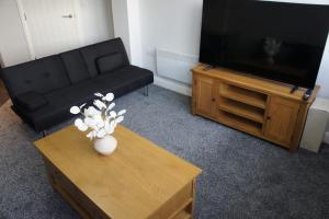 un salon avec un canapé noir et une télévision dans l'établissement Melbourne House Gem Stylish 2-bed In City Centre, à Accrington