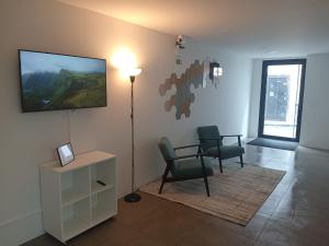 een woonkamer met 2 stoelen en een tv aan de muur bij Apartamento Sonho Terra in Ponta Delgada