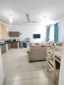 a living room with two couches and a kitchen at Tee,s Homestay in Mtwapa