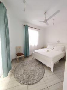 a bedroom with a white bed and a rug at Tee,s Homestay in Mtwapa