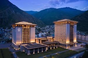 a hotel with two towers with mountains in the background at Delta Hotels by Marriott Jiuzhaigou in Jiuzhaigou