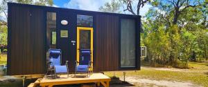 a tiny house with chairs sitting on a table at Wilderness Whisper By Tiny Away in Agnes Water