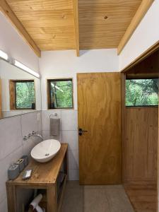 a bathroom with a sink and a wooden door at Cabaña Oma Iguazú in Puerto Iguazú