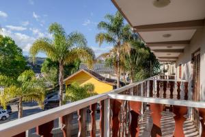 un balcon avec des palmiers et une maison jaune dans l'établissement Pousada Portal da Serra, à Campos do Jordão