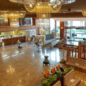 a large room with a lobby with chandeliers at 佐久一萬里温泉ホテル in Saku
