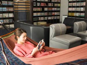 a woman sitting in a hammock in a library at 佐久一萬里温泉ホテル in Saku