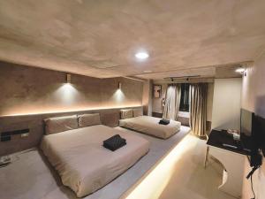 a bedroom with two beds and a flat screen tv at 艾睏設計行旅 Sleepie Design Hotel in T'ien-liao
