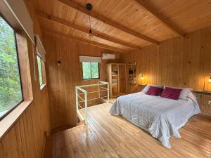 a bedroom with a bed in a wooden cabin at Cabaña Oma Iguazú in Puerto Iguazú +17 photos