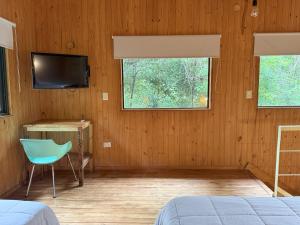 a bedroom with a bed and a television and a chair at Cabaña Oma Iguazú in Puerto Iguazú
