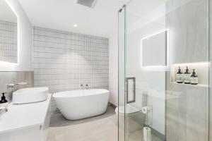 ein weißes Badezimmer mit Badewanne und Waschbecken in der Unterkunft Modern 3-Bed Villa with Mountain Views in Wanaka + 15 Fotos