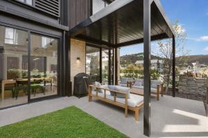 ein Haus mit einer Veranda mit einem Sofa und einem Tisch in der Unterkunft Modern 3-Bed Villa with Mountain Views in Wanaka