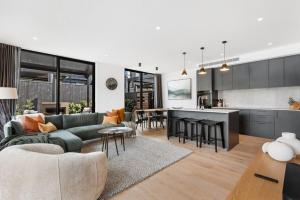 ein Wohnzimmer mit einer grünen Couch und einer Küche in der Unterkunft Modern 3-Bed Villa with Mountain Views in Wanaka